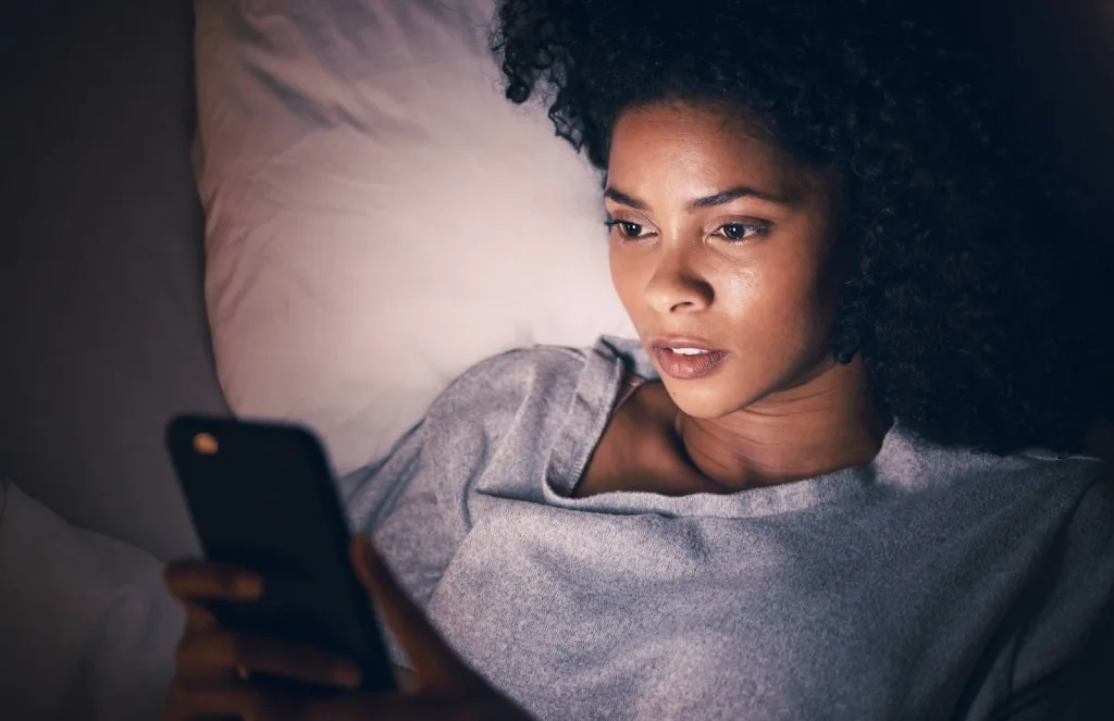 woman in bed scrolling phone revenge sleep procrastination concept